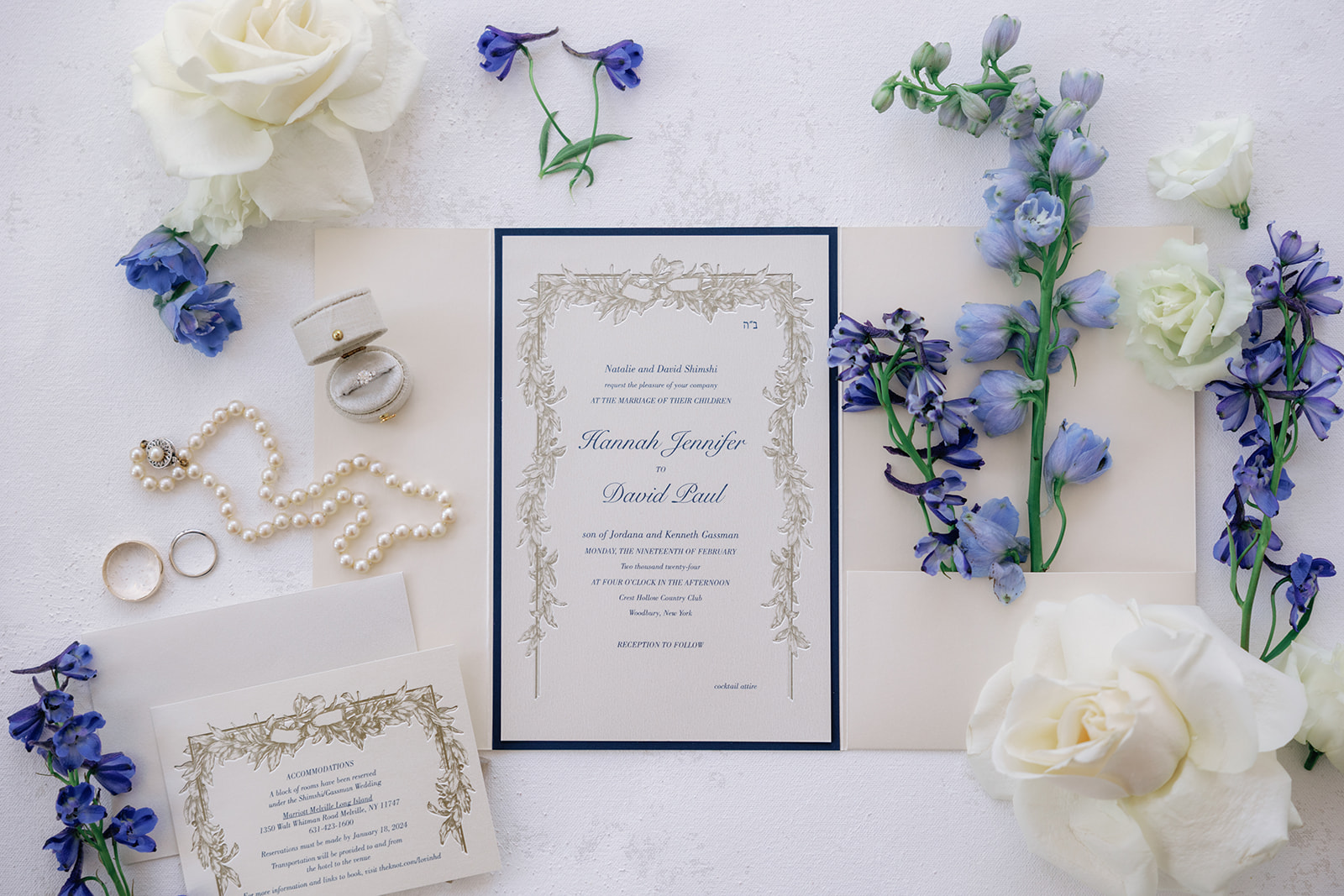 Details of a bride's invitations, flowers and jewelry sitting on a table