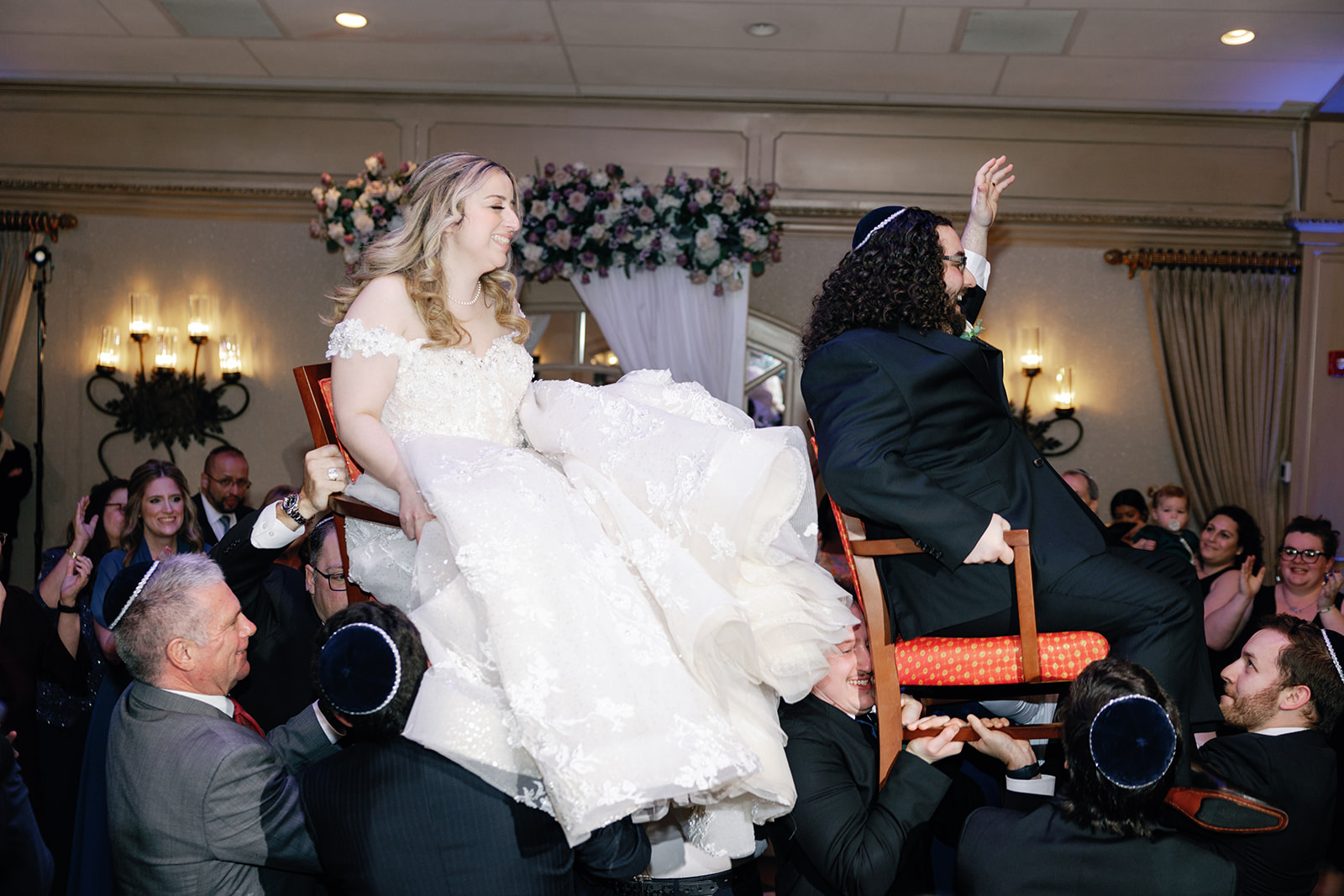 Newlyweds laugh and celebrate while being lifted on chairs at their Crest Hollow Country Club Wedding reception