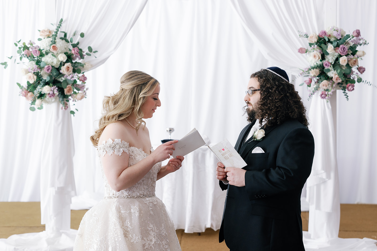 Newlyweds read each other cards they wrote for each other while standing at an altar