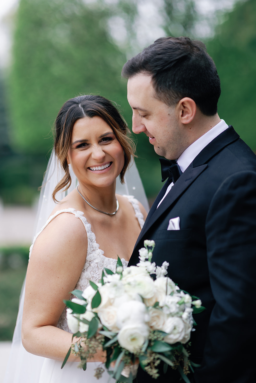 A bride laughs while standing close to her groom in a garden at Castle Wedding Venues in NJ