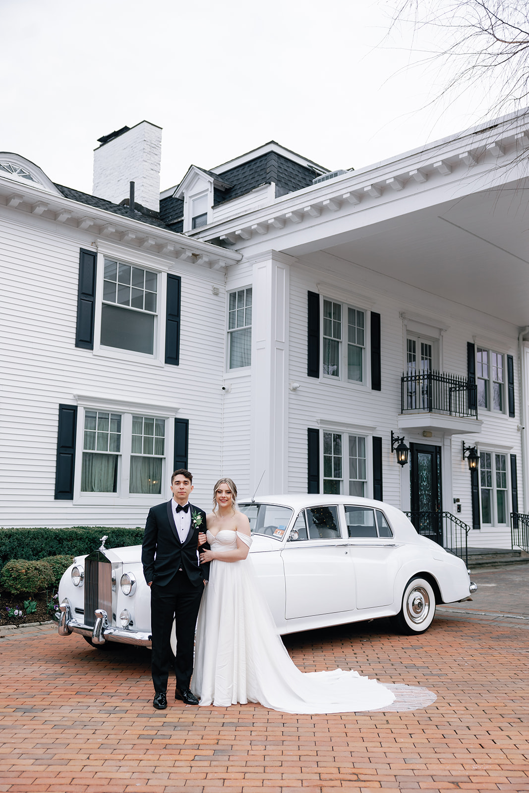 Newlyweds stand in front of a vintage car parked outside one of the New Jersey Garden Wedding Venues