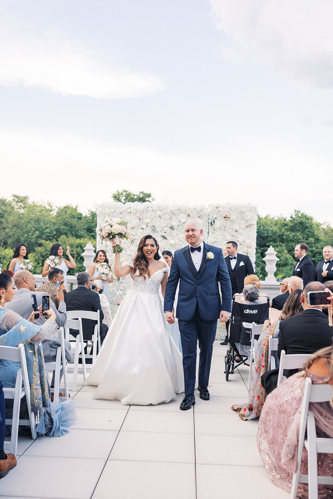 Happy newlyweds walk up the aisle holding hands and celebrating at one of the New Jersey Mansion Wedding Venues