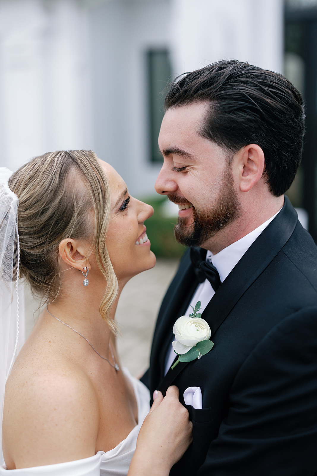 Happy newlyweds share a smile and intimate moment in a black tux and silk dress