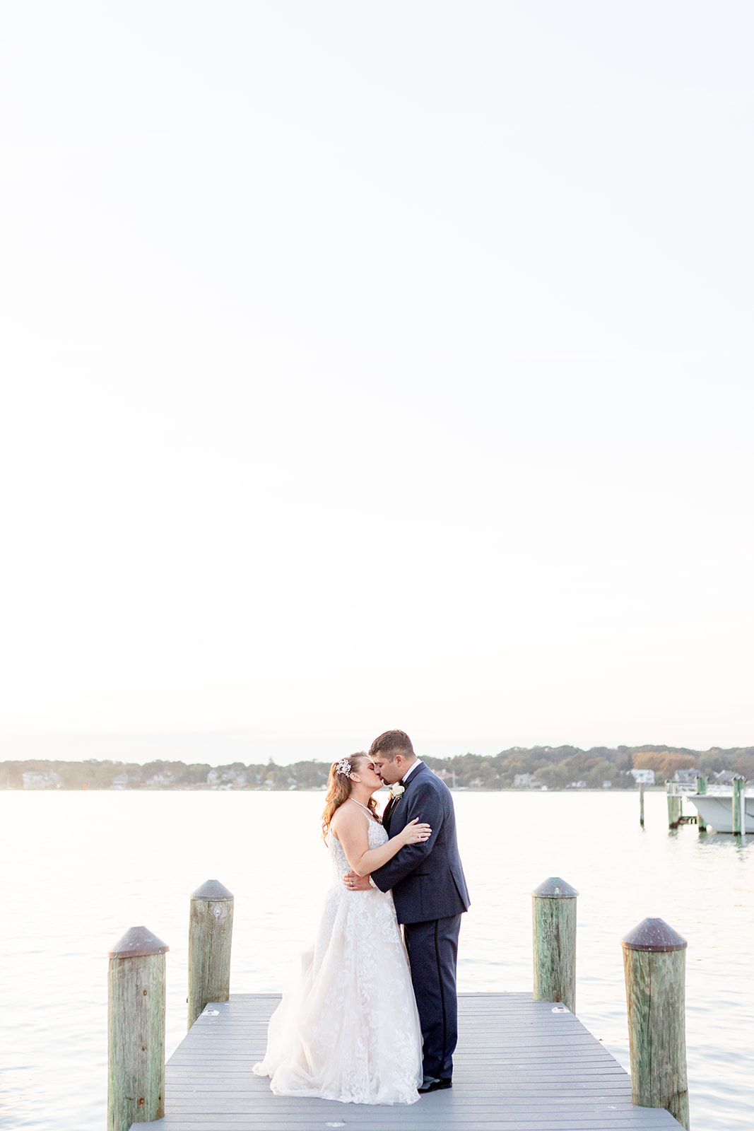 Newlyweds kiss on a lake dock at sunset