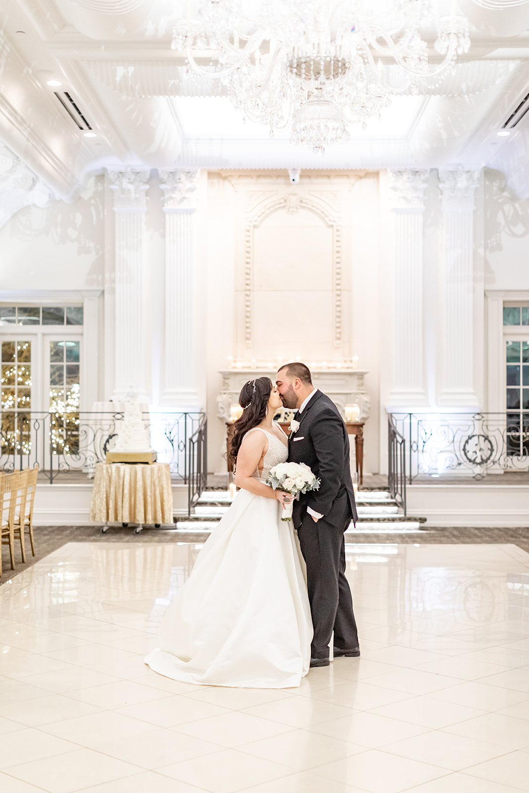 Newlyweds kiss on the dance floor under a crystal chandelier at Nanina’s In the Park