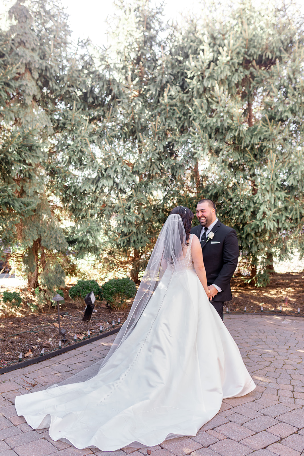 A bride and groom share an intimate first look in a garden with huge smiles at their Nanina's In the Park wedding