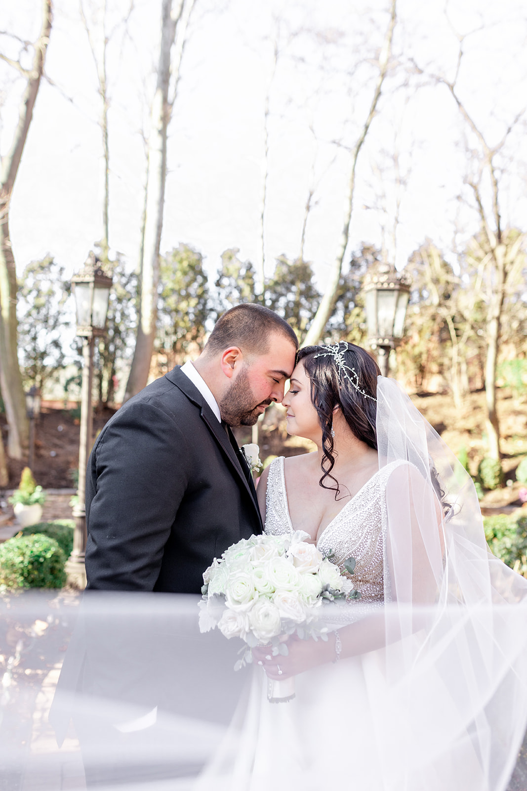 Newlyweds touch foreheads while the veil flies around them at their Nanina’s In the Park wedding