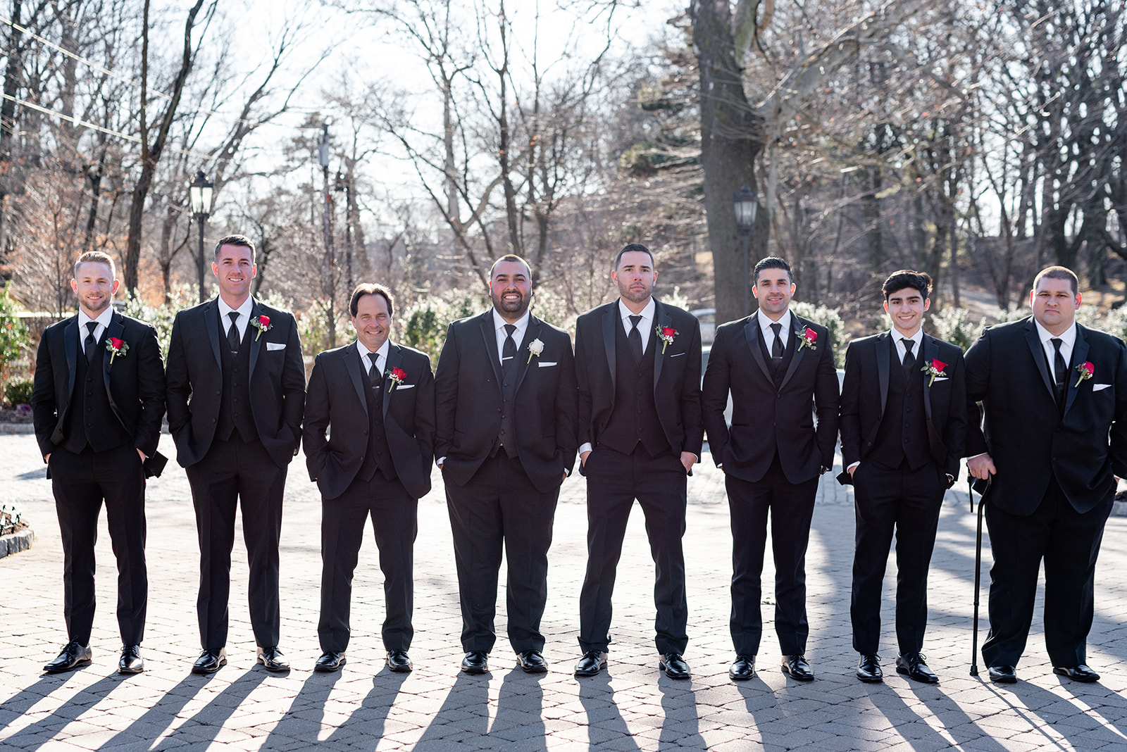 A groom stands in a black suit with his large wedding party