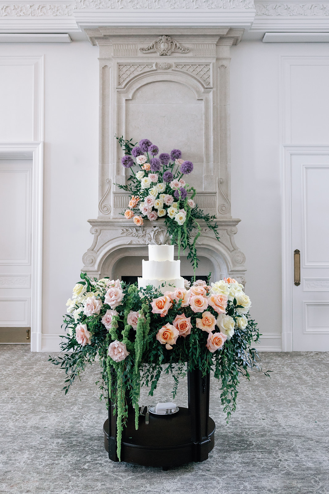 Details of a wedding cake sitting on an ornate stand covered in roses at a Park Chateau Wedding